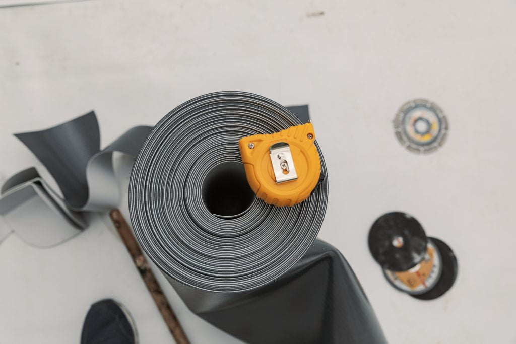 Roll of epdm membrane topped with tape measure and broom handle - used to signify epdm tools
